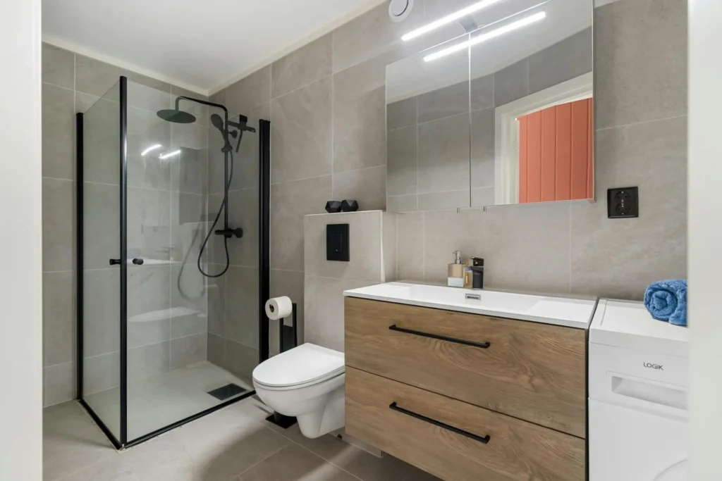 Drempelloze inloopdouche in Ninove met wandgoot, grote vloertegels en glazen wand door B-Renovation