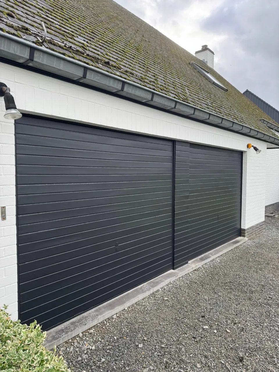 Wit geschilderde gevel naast een antraciet garagepoort