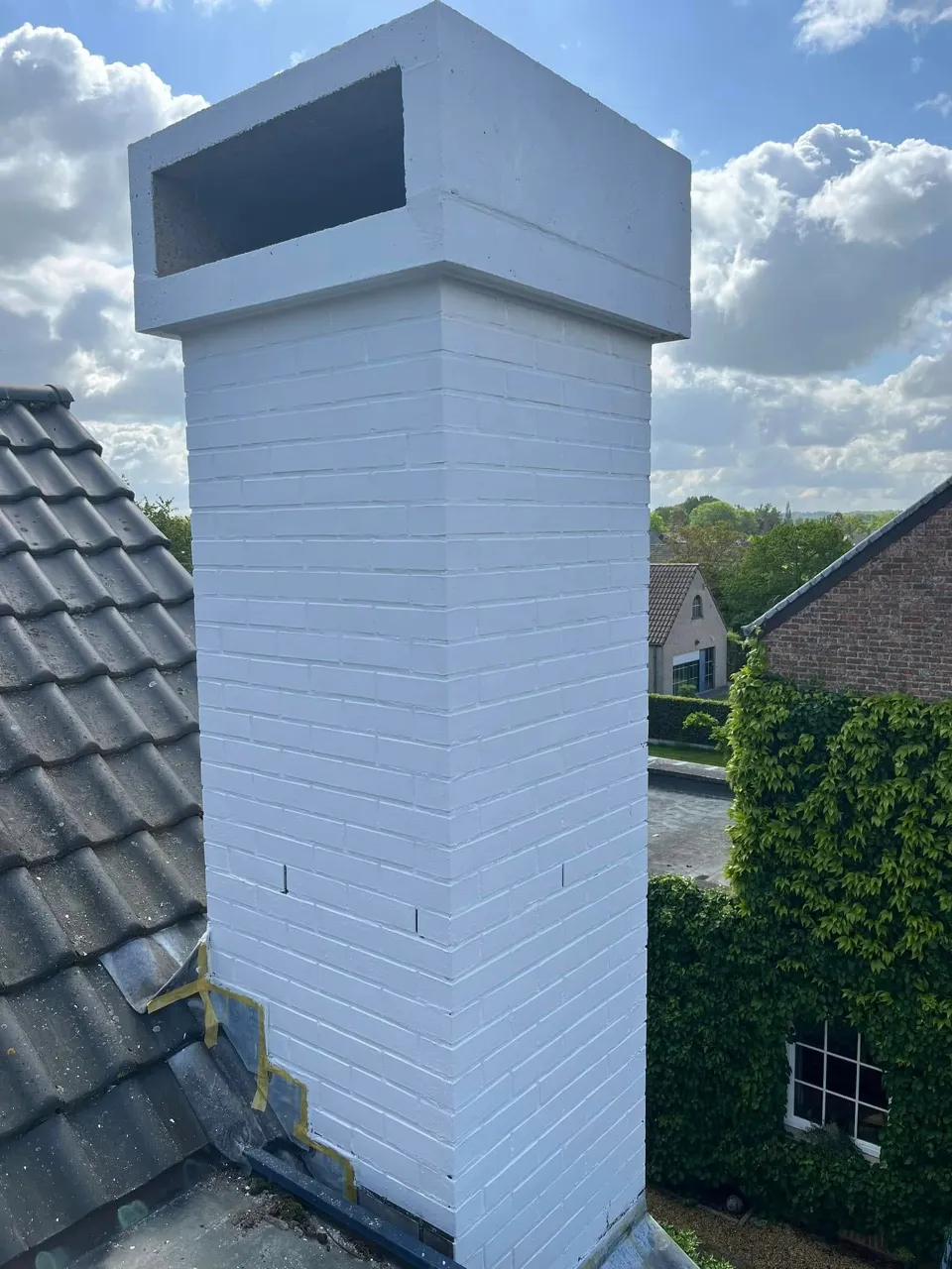 Wit geschilderde schoorsteen op een pannendak