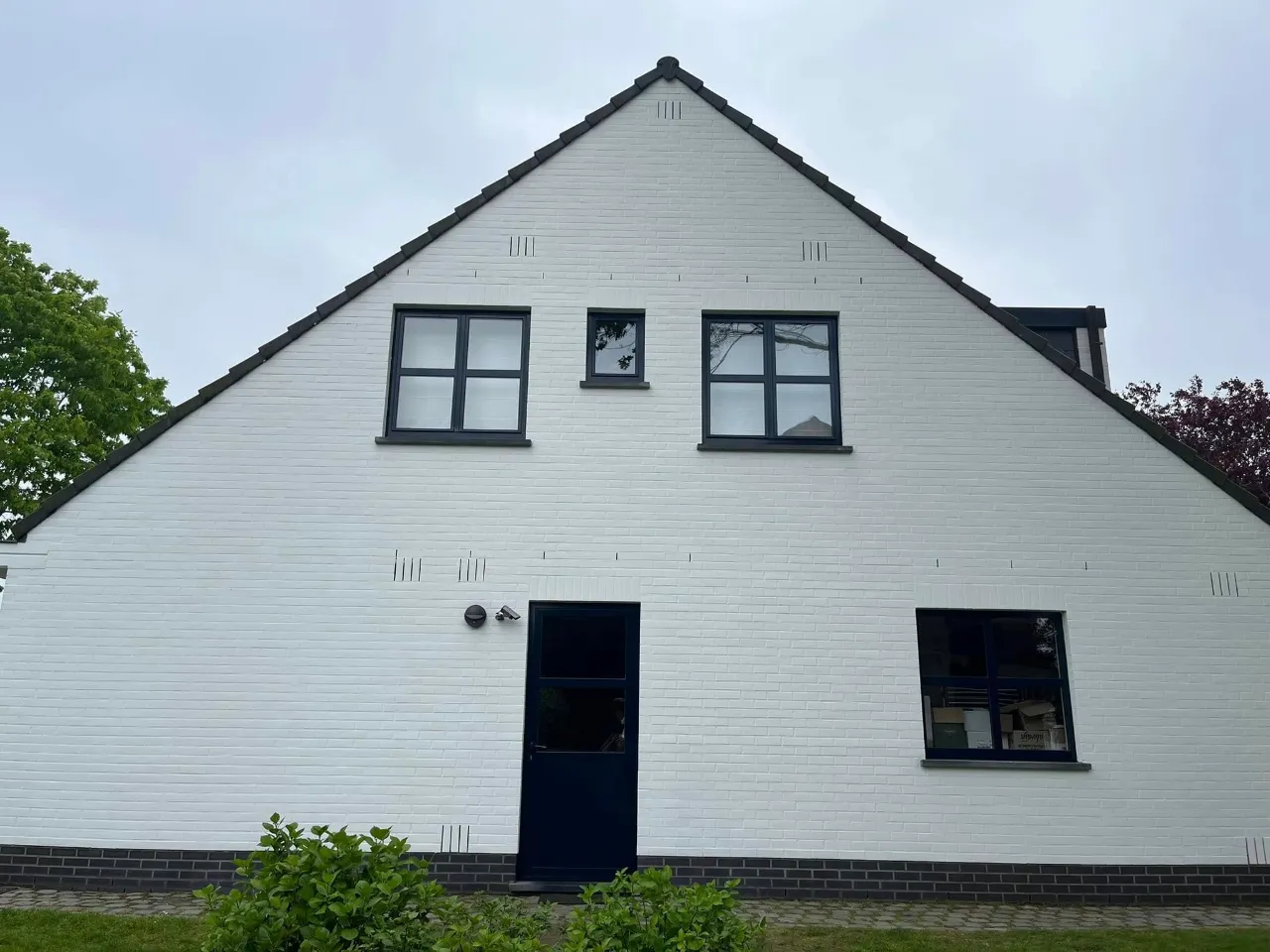Witte gevel met puntdak na buitenschilderwerk door B-Renovation